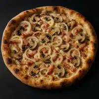 Pizza artisanale à croûte dorée, garnie de champignons tranchés, lardons et oignons blancs sur une base crémeuse.