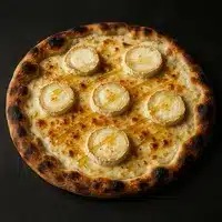 Pizza gourmande avec base de fromage crémeux, cinq ronds de chèvre chaud et un filet de miel doré, croûte bien dorée et légèrement noircie.