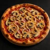 Pizza ronde cuite sur croûte dorée, garnie de sauce tomate, fromage, fines tranches de jambon et champignons de Paris, avec des rondelles d'oignon.