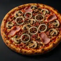 Pizza garnie de viande hachée, tranches de jambon, champignons émincés et rondelles d'oignon blanc sur une croûte dorée, sur fond noir.