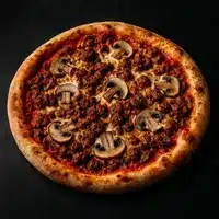 Pizza ronde à croûte dorée, généreusement garnie de sauce tomate et de viande hachée brune, parsemée de tranches de champignons. Vue de dessus sur fond sombre.